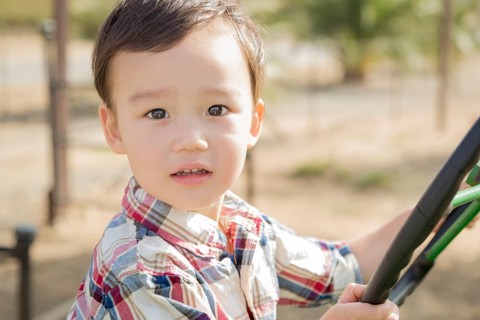 Adorable mixed-race young boy playing on the tractor at the pumpkin patch
