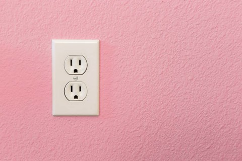 Electrical sockets in colorful pink wall of house