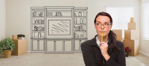 Woman inside room with moving boxes glancing toward entertainment unit drawing on wall
