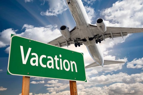 Vacation green road sign and airplane above with dramatic blue sky and clouds