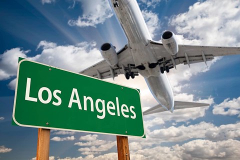 Los angeles green road sign and airplane above with dramatic blue sky and clouds