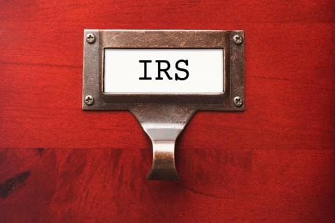 Lustrous wooden cabinet with I. R. S. file label in dramatic light