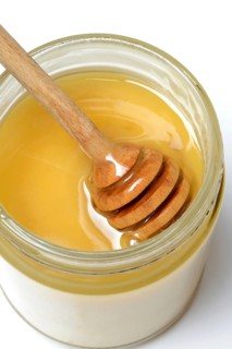 Cremiger Bienenhonig in Glas und Honigloeffel
