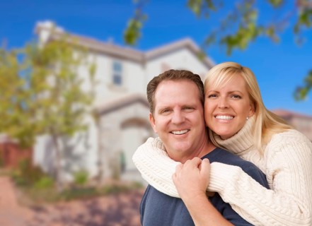 Happy couple hugging in front of a beautiful house