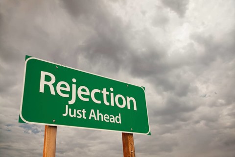Rejection just ahead green road sign with dramatic storm clouds and sky
