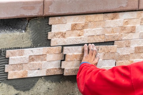 Worker installing wall tile at construction site