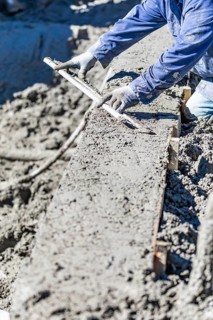 Pool construction worker working with A smoother rod on wet concrete