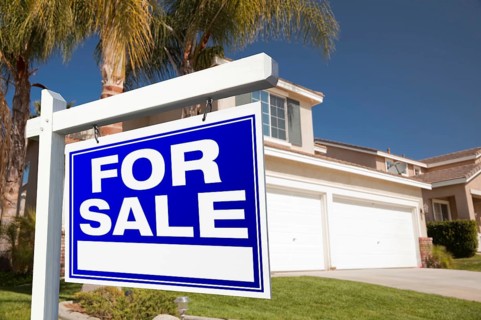 For sale real estate sign in front of house