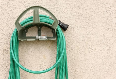 Garden hose hanging on stucco wall