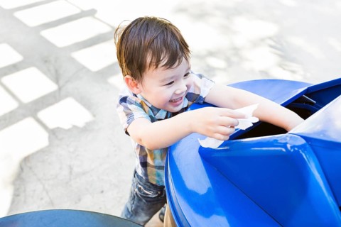 Happy cute mixed-race boy placing paper into the recycle bin