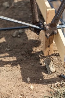 Worker using tools to bend steel rebar at construction site