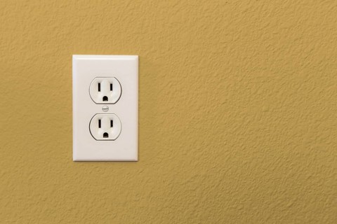 Electrical sockets in colorful mustard yellow wall of house