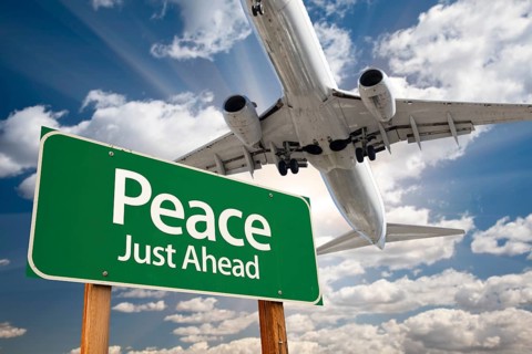 Peace green road sign and airplane above with dramatic blue sky and clouds