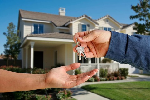Handing over the house keys in front of a beautiful new home