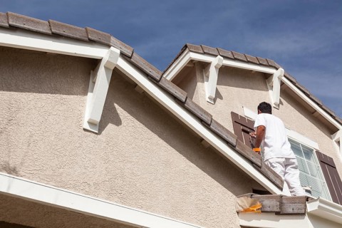 Busy house painter painting the trim and shutters of A home