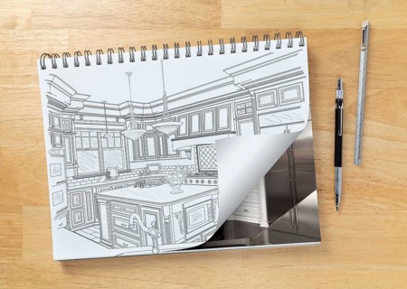 Sketch pad on desk with drawing of custom kitchen and page corner turning to show finished construction next to engineering pencil and ruler scale
