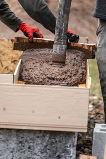 Construction workers pouring and leveling wet cement into wood framing