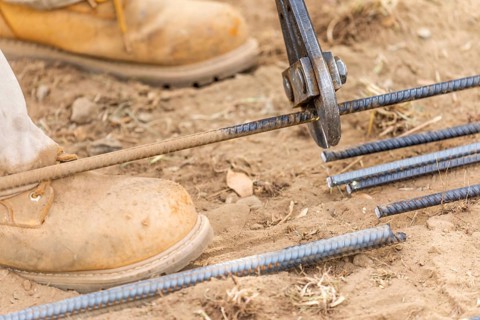 Worker cutting steel rebar at construction site abstract