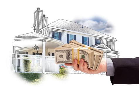 Hand holding thousands of dollars in cash over house drawing and photo area