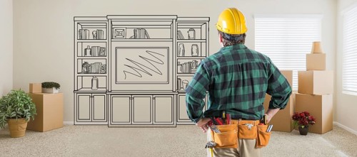 Contractor inside room with boxes facing entertainment unit drawing on wall