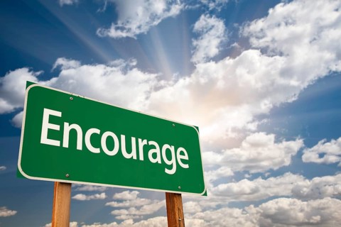 Encourage green road sign with dramatic clouds and sky