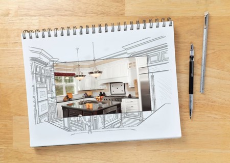 Sketch pad on desk with drawing of custom kitchen and square section showing finished construction next to engineering pencil and ruler scale