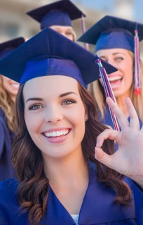 Happy graduating group of girls in cap and gown celebrating on campus