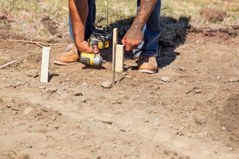 Worker installing stakes and lumber guides at construction site
