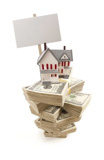 Small house on stacks of hundred dollar bills and blank sign isolated on a white background