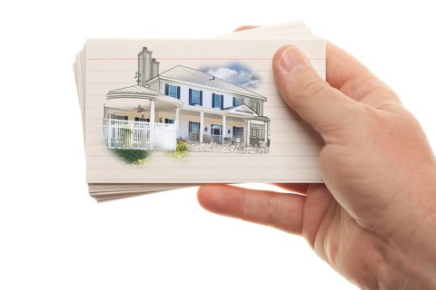 Male hand holding stack of flash cards with house drawing isolated on a white background