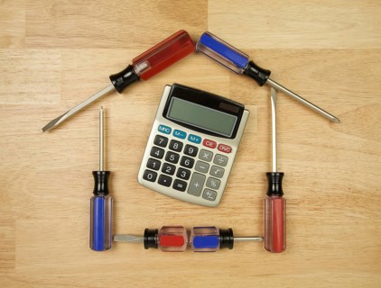 House shaped by screwdrivers and calculator on a wood background