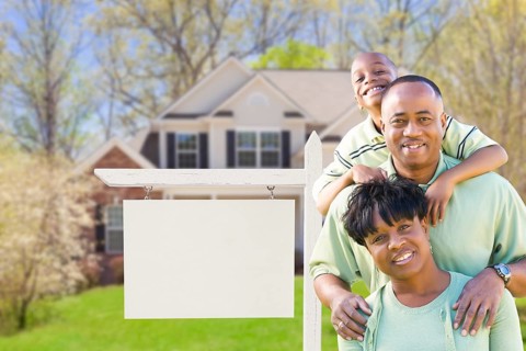 African american family in front of blank real estate sign and new house
