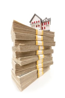Small house on stacks of hundred dollar bills isolated on a white background