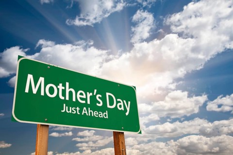 Mother's day green road sign on dramatic blue sky with clouds