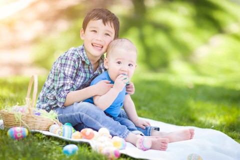 mixed-race chinese and caucasian boys outside in park playing with easter eggs