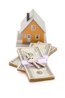 Home and house keys on stack of money isolated on a white background
