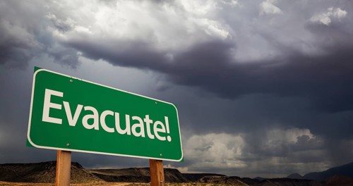 Evacuate green road sign with dramatic clouds and rain