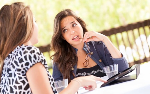 Expressive young adult girlfriends using their computer electronics outdoors