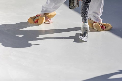 Worker wearing sponges on shoes smoothing wet pool plaster with trowel