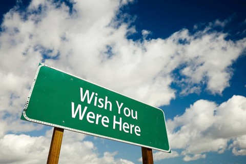 Wish you were here road sign with dramatic clouds and sky