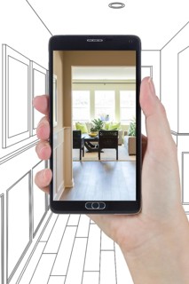 Hand holding smart phone displaying photo of the house hallway drawing behind