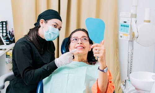 Satisfied female client in dental clinic looking at mirror
