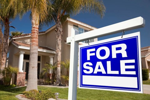 For sale real estate sign in front of house