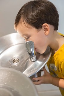 mixed-race boy drinking from the fresh water fountain
