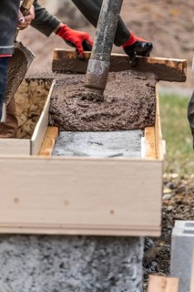 Construction workers pouring and leveling wet cement into wood framing