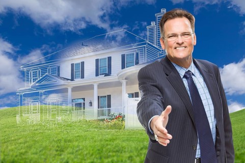 Smiling male agent reaching for hand shake in front of ghosted new house