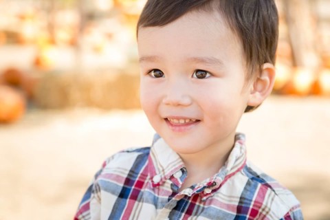 Cute mixed-race young boy having fun at the pumpkin patch