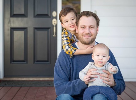Young mixed-race father and sons on front porch