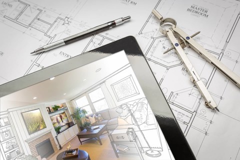 Computer tablet showing living room illustration sitting on house plans with pencil and compass