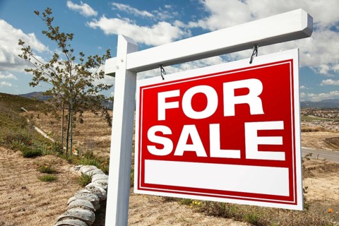 For sale real estate sign and emtpy construction lots